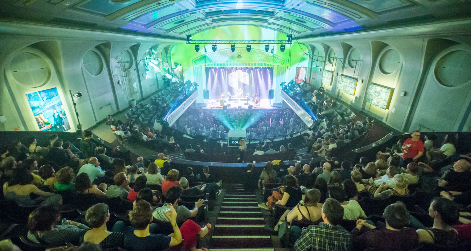 Leith Theatre. Credit: Chris Scott & Theatres Trust Taken from the top balcony, looking down at the full theatre audience watching the stage with a band and musicians playing and green lighting.