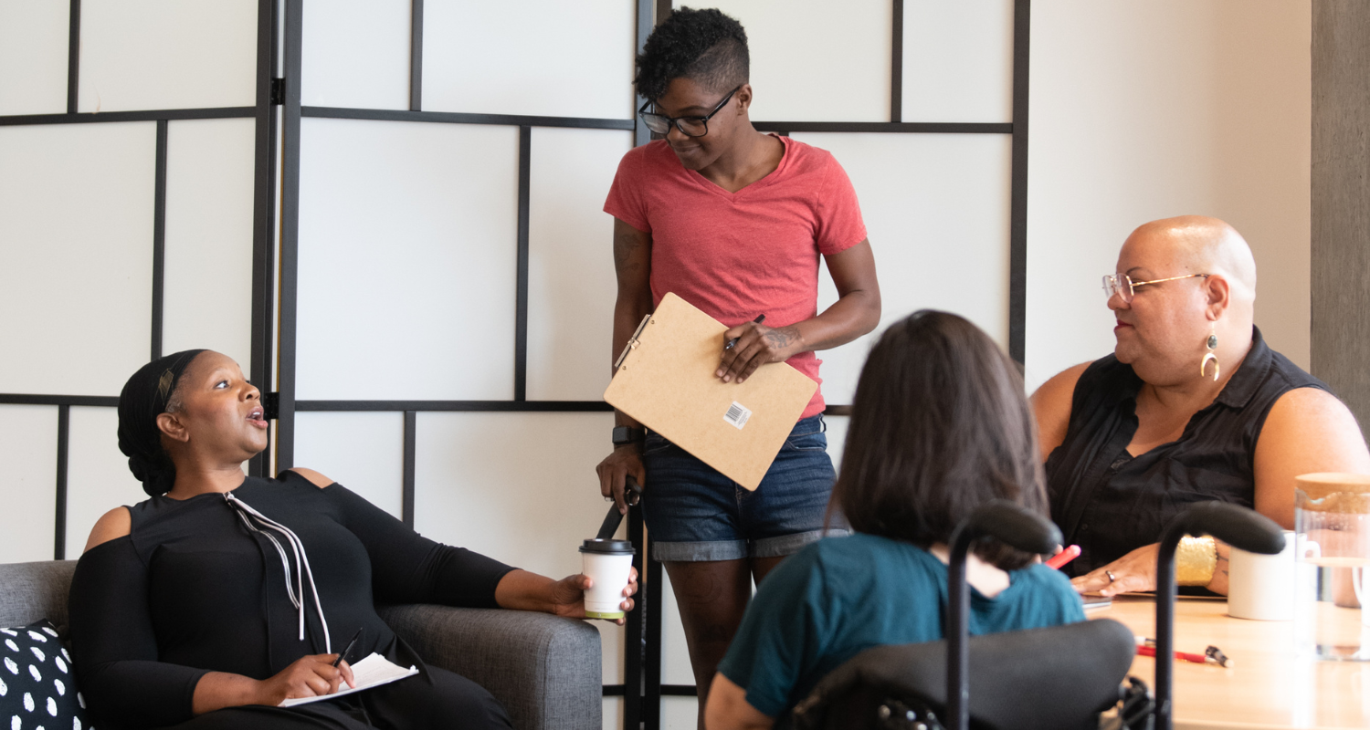 Disabled and here – (Credit: CC BY 4.0) Four disabled people of colour having a meeting and chatting to each other. Credit: Disabled and here, CC BY 4.0