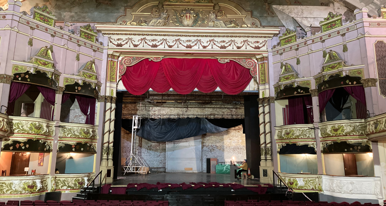 Morecambe Winter Gardens. Credit: Theatres Trust An empty, white and gold theatre auditorium and stage with red chairs, stage and gold decorations on the wall, boxes and ceiling.