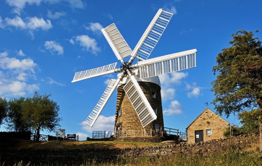 Heage Windmill Society A six sailed windmill with white sails and sandy stone in the green countryside
