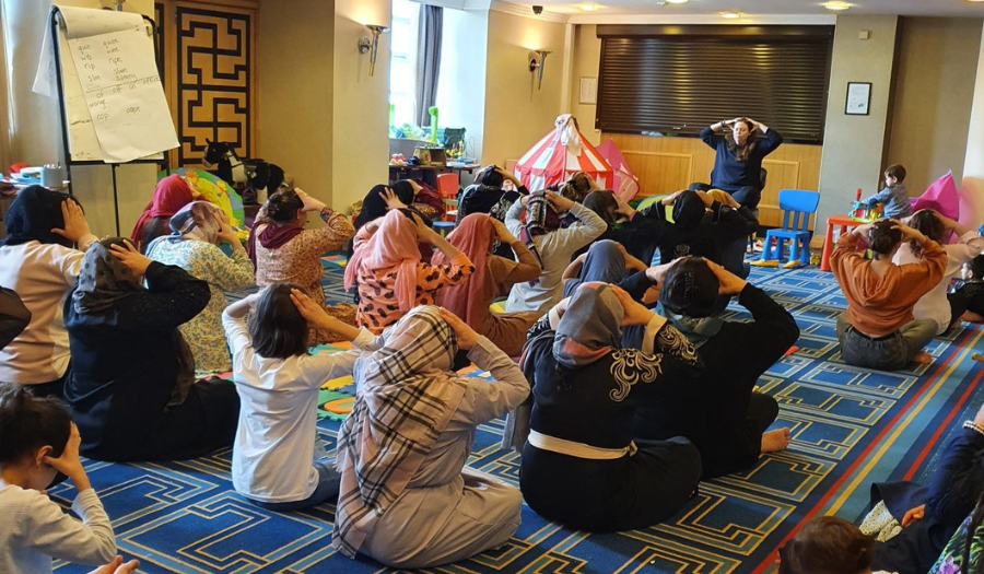 Yoga class- (Credit: Refugee Women Connect) A group of women of different ages do a yoga class in a carpeted room