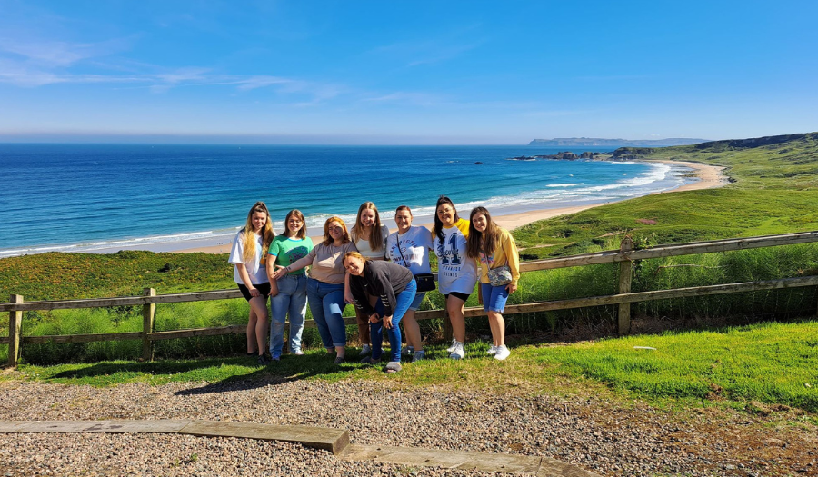 Girls Outing- (Credit: Northern Ireland Youth Forum) A group of young girls pose for a picture, on a glorious day with a field and beach in the background.